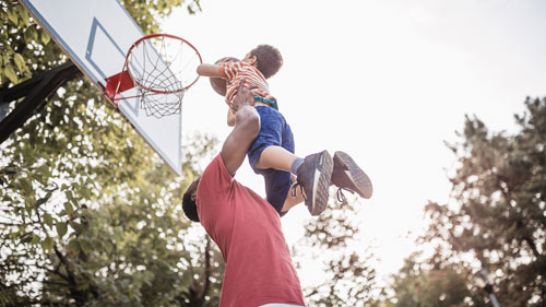 Photo of a father lifting his young son with a basketball